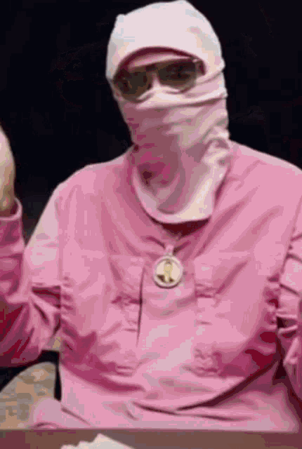 a man wearing a pink jacket and a pink mask and sunglasses .