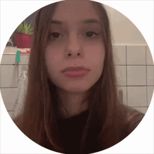 a woman 's face is shown in a circle against a tiled wall