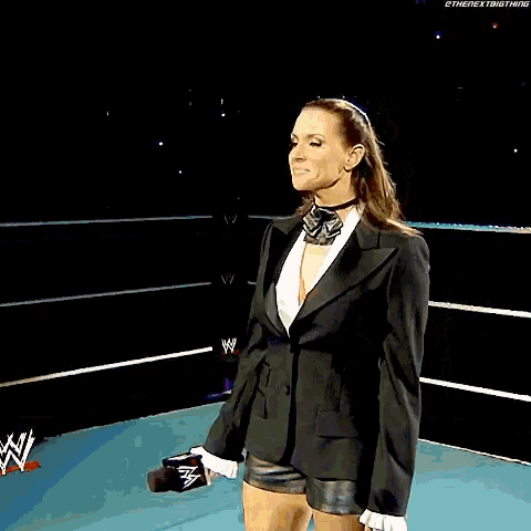 a woman in a tuxedo stands in front of a sign that says wrestlemania principal owner of stephanie mcmahon