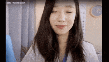 a woman in a lab coat is smiling in front of a body physical exam clock
