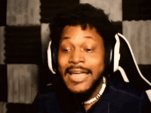 a man wearing headphones and a necklace is making a funny face .