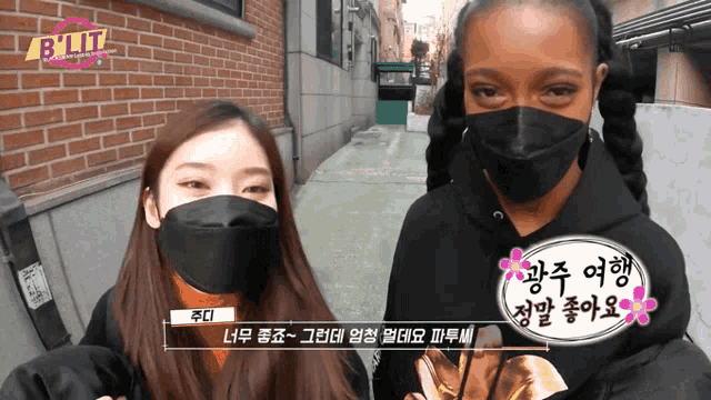 two women wearing face masks are standing next to each other in front of a sign that says ' exit '