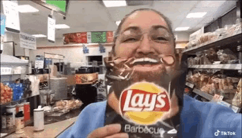 a woman with a beard is holding a bag of lays chips