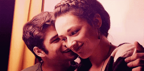 a man is kissing a woman on the cheek while the woman smiles .