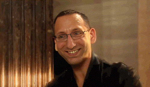 a man with glasses and a black shirt smiles for the camera