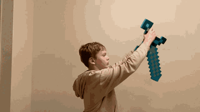 a boy is holding a blue minecraft sword in his hand
