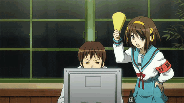 a girl holding a megaphone stands next to a man looking at a computer screen