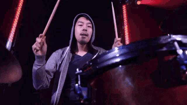 a man in a hooded sweatshirt is playing drums