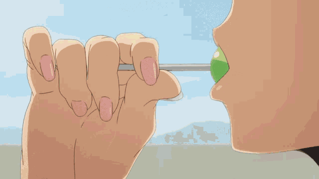 a person with pink nail polish is licking a green lollipop