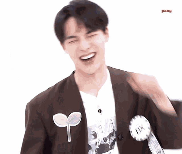 a young man wearing a brown jacket and a white t-shirt is smiling with the word pang on the bottom right