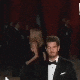 a man with a beard wearing a tuxedo and bow tie is making a funny face .
