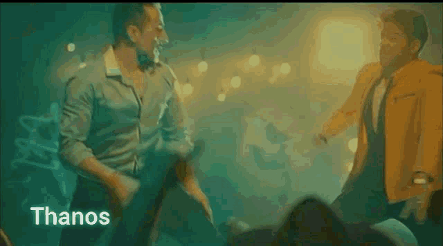 two men are dancing in a dark room and the word thanos is visible in the corner