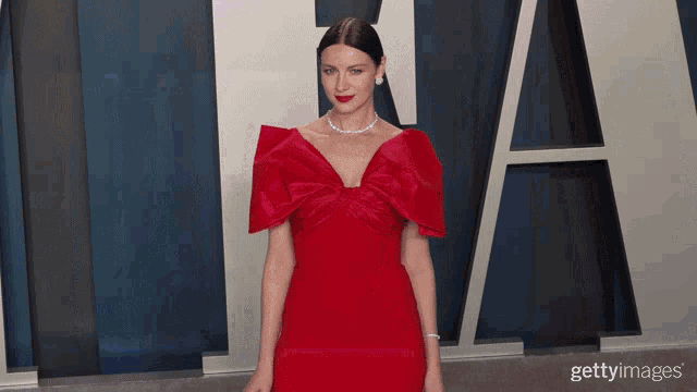 a woman in a red dress is standing in front of a large a