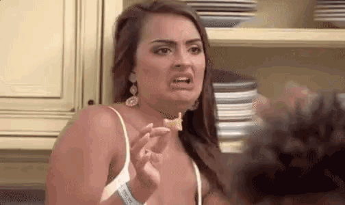a woman is holding a piece of food in her hand and making a face .