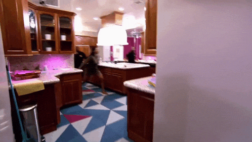a woman is dancing in a kitchen with a geometric patterned floor