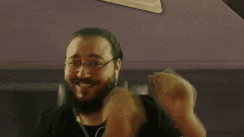 a man with a beard and glasses is sitting in a chair .