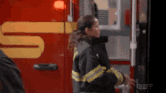 a woman in a firefighter 's uniform is standing next to an ambulance .