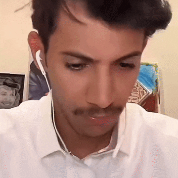 a man with a mustache wearing ear buds looks down at something