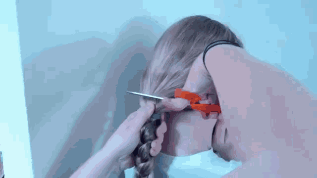 a person is cutting a woman 's hair with a pair of scissors