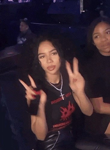 a woman wearing a black t-shirt that says insight on it giving a peace sign