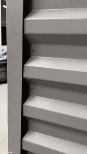 a close up of a gray metal staircase with a car in the background .