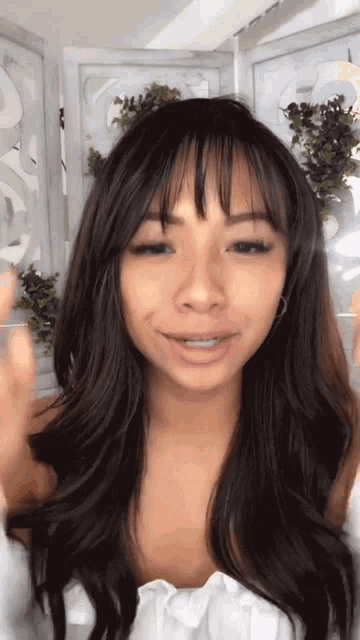 a woman with long dark hair is wearing a white shirt