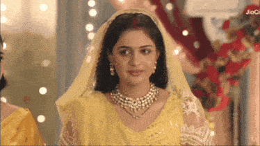 a woman in a yellow dress with a red bindi on her forehead stands in front of a sign that says jioci