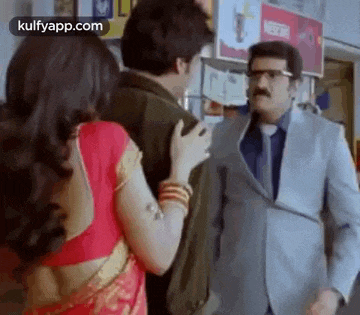 a man in a suit and tie is talking to a woman in a red saree .