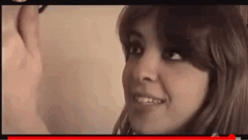 a woman is smiling and looking at a man in a video .