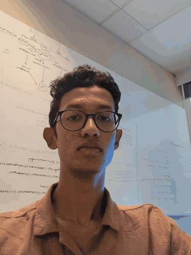 a man wearing glasses stands in front of a white board with a diagram on it that says ' a '