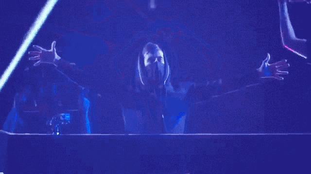 a man in a mask stands in front of a blue screen