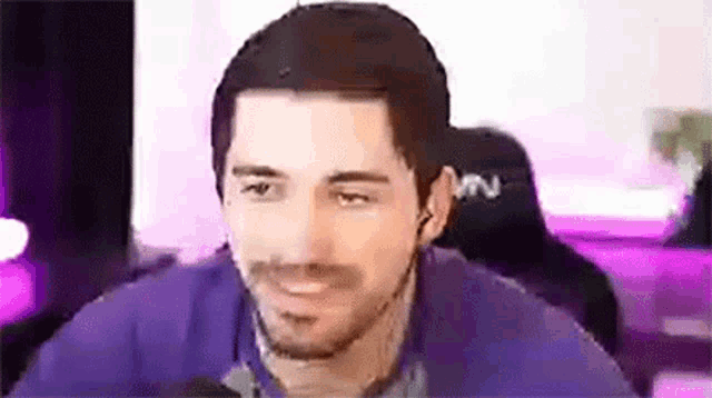 a man with a beard is smiling and looking at the camera while sitting in front of a computer .