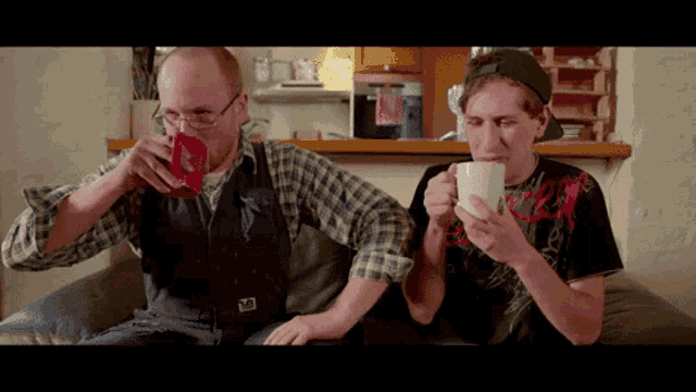 a man wearing a plaid shirt is drinking from a red cup