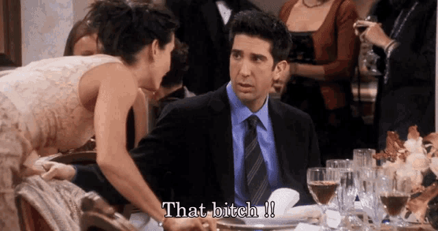 a man and a woman are sitting at a table and the woman is saying that bitch !!