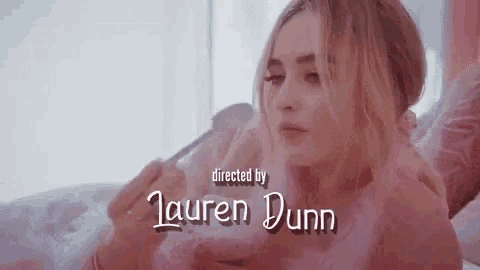 a woman is laying in a bathtub with a spoon in her hand and the name lauren dunn is on the bottom .