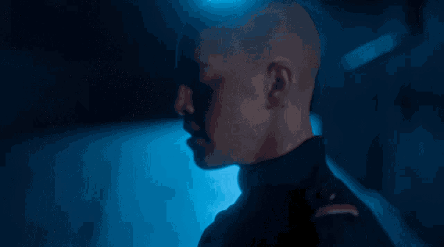 a man with a shaved head is wearing a uniform