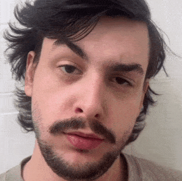a man with a beard looks at the camera with a serious look on his face