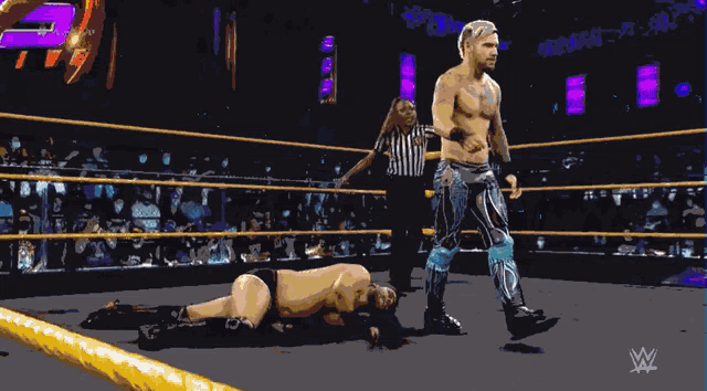 a wrestler is standing in a wrestling ring with a referee