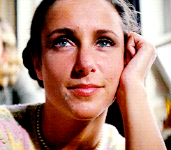 a close up of a woman 's face with a hand on her ear