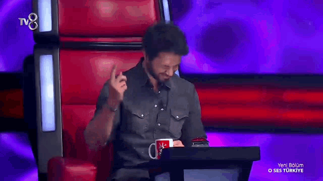a man sitting in a chair with a tv8 logo on the bottom left