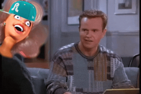 a man sitting next to a barbie doll wearing a hat that says r on it
