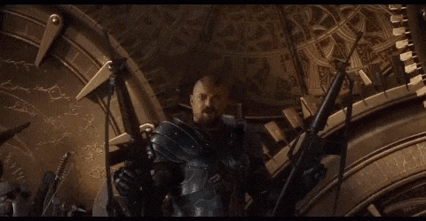 a man in armor is holding a bow and arrow in front of a large clock .