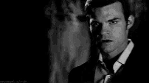 a man in a suit and tie is standing in a dark room .