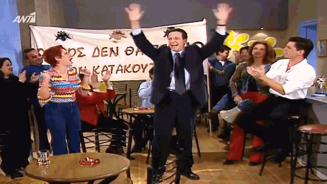 a man holds up his arms in front of a banner that says ant