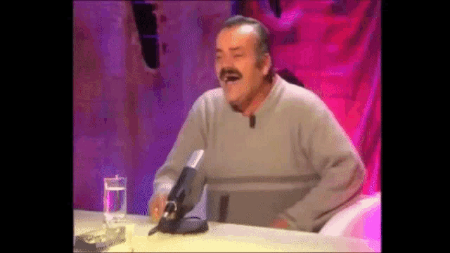 a man is sitting at a table with a glass of water and a microphone .