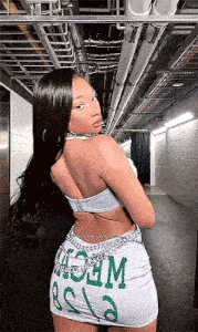 a woman is standing in a hallway wearing a white dress and a crop top .