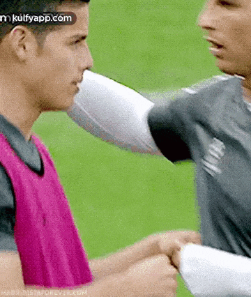 two men are shaking hands on a soccer field with a watermark that says kulfyapp.com