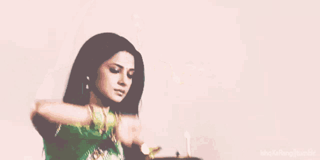 a woman in a green dress holds a candle in her hand