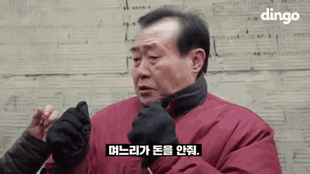 a man wearing a red jacket and black gloves is talking to someone in a foreign language .