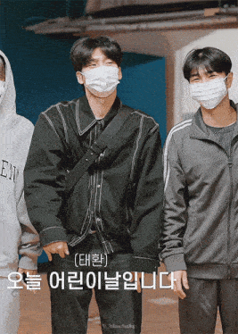 a man wearing a mask stands next to another man wearing a hoodie